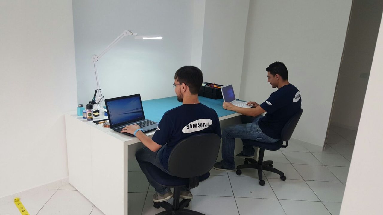 Técnicos da Fast Fix consertando aparelhos na bancada, em Curitiba