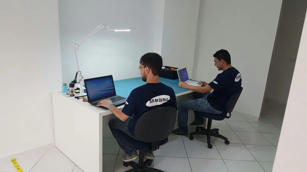 Técnicos da Fast Fix consertando aparelhos na bancada, em Curitiba